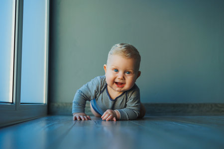 Portrait of a small baby boy in a cotton bodysuit with a smile on his face. The face of a blue-eyed baby with a smile.の写真素材