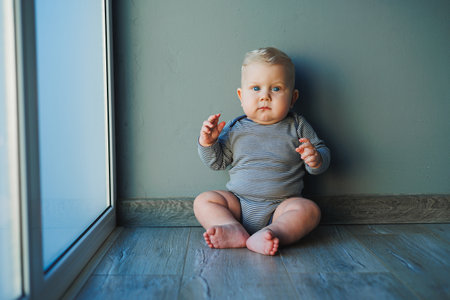 Cute little boy in a bodysuit with a smile on his face. The child looks at the camera, smiles. Clothes for babiesの写真素材