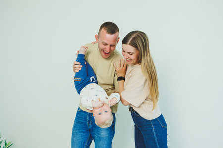 A young family is playing and kissing a newborn baby and smiling, a loving family is holding their...
