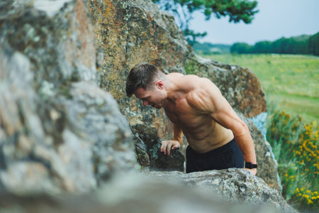 A young man with abs cubes on the background of the forest. Athletic pumped-up man on a rock background.の写真素材