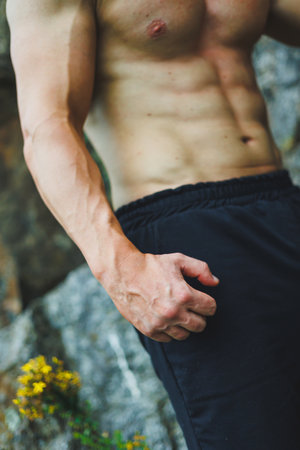 Photo of an athlete, a muscular, athletic young man doing exercises with a naked torso, in the forest, mountains.の写真素材