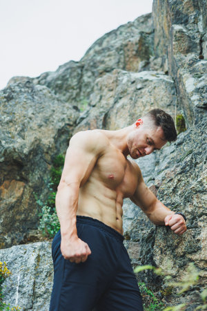 Photo of an athlete, a muscular, athletic young man doing exercises with a naked torso, in the forest, mountains.の写真素材