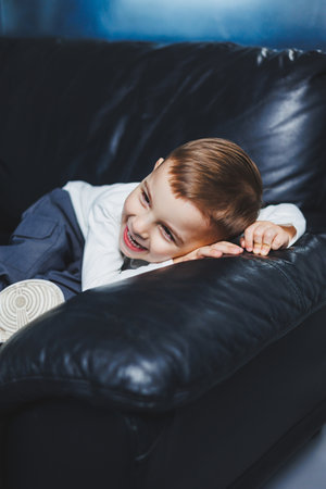 A 3-year-old boy in a white sweater and pants with a smile on his face. Little boy in stylish clothes.の写真素材