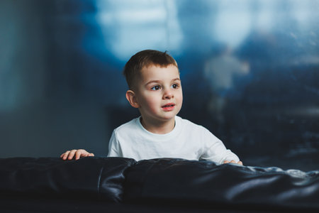 Happy little boy on sofa, three-year-old cheerful boy in stylish clothes.の写真素材