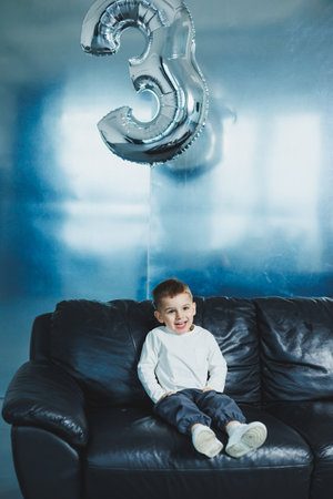 Happy little boy on sofa, three-year-old cheerful boy in stylish clothes.の写真素材