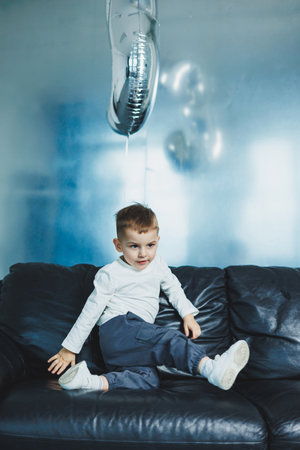 Happy little boy on sofa, three-year-old cheerful boy in stylish clothes.の写真素材
