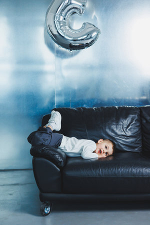 Happy little boy on sofa, three-year-old cheerful boy in stylish clothes.の写真素材