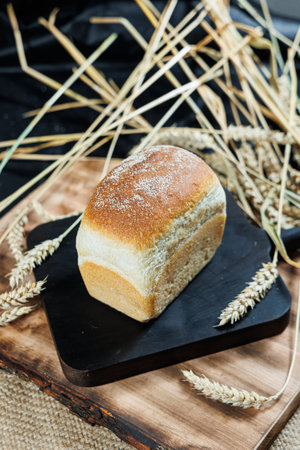 Concept of bread on a wooden table. Ruddy brown loaves of bread stand on a table sprinkled with...