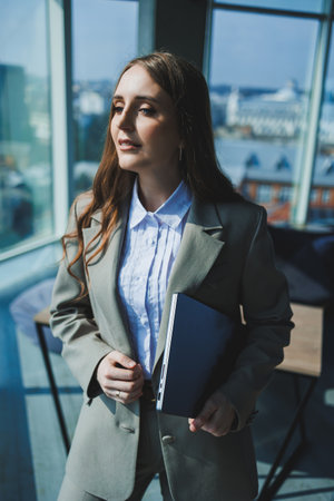 A young woman in a gray suit is working on a laptop in a cafe. Beautiful girl in casual clothes.の写真素材