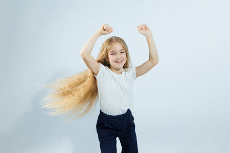 Young beautiful girl with long curly hair in jeans and a white t-shirt on a white background. Different emotions on the girl's face.の写真素材