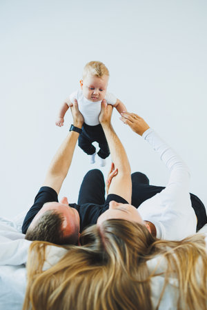 Mother father holding baby toddler. Happy family at home. Mom dad and son playing fun together. A...
