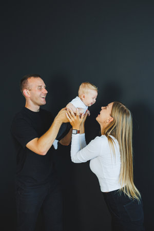 Cute young family mom dad and newborn baby smiling three of them at home. A happy family couple with...