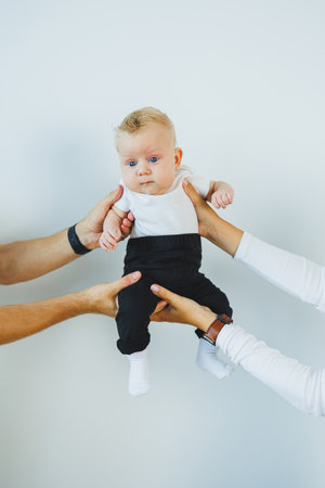 Close-up of a two-month-old baby in the hands of his parents. A baby with white hair and blue eyes.の写真素材