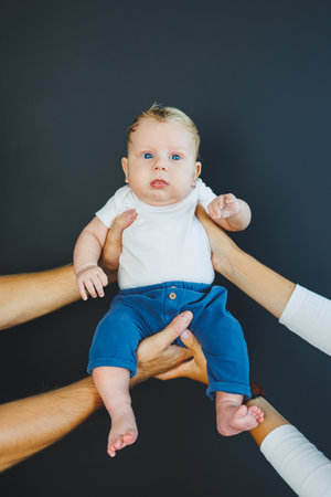 Close-up of a two-month-old baby in the hands of his parents. A baby with white hair and blue eyes.