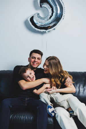 A young married couple hugs their son. Mom, dad and son at home on the sofa. A happy family.の写真素材
