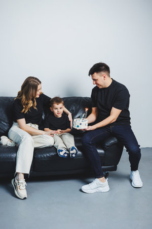 A young married couple hugs their son. Mom, dad and son at home on the sofa. A happy family.の写真素材