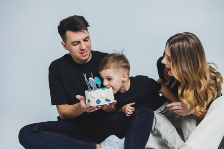 Happy family couple celebrating their son's birthday on a white background. mom dad and son with cakeの写真素材