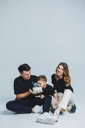 Happy family couple celebrating their son's birthday on a white background. mom dad and son with cakeの写真素材