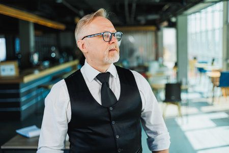 Portrait of an old bearded businessman in a white shirt and tie with glasses on his face. Business gray-haired man in the office.の写真素材