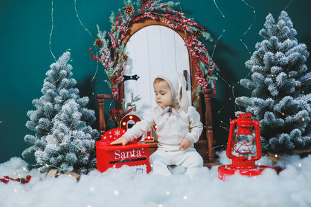 A 1-year-old boy is sitting on the background of New Year's decorations. New Year's mood. Child on the background of Christmas treesの写真素材