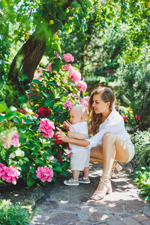A young happy mother holds her one-year-old son in her arms during a walk. A loving mother hugs her son.の写真素材