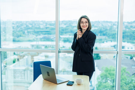 Businesswomen with coffee working on laptop in office, happy beautiful businesswomen in formal suit working at workplace. Emotions of a woman in the office.の写真素材