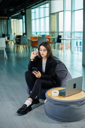 Young smiling professional businesswoman, happy confident female sales manager standing in modern office working online. A modern woman works on a laptopの写真素材