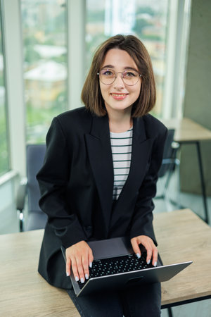 Woman business manager smiling working on laptop in office. An employee works in an office with...