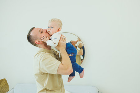 Young smiling dad is playing with his newborn son. Dad and little son.