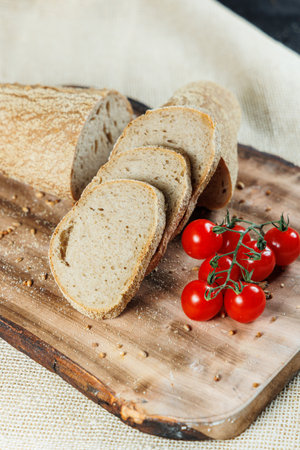 Fresh craft bread sliced on a wooden board on a dark concrete background. Homemade baking