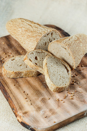 Fresh craft bread sliced on a wooden board on a dark concrete background. Homemade baking