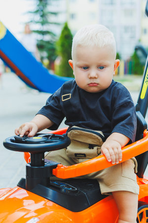 A little boy, 1 year old, sits in a plastic car. A machine for feeding babies. Tolokar for children.