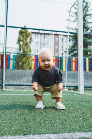 A child is having fun playing in an open field. A little boy in a t-shirt and shorts is playing on the street. Stylish children's clothing. A boy in summer crocs on his feet.の写真素材