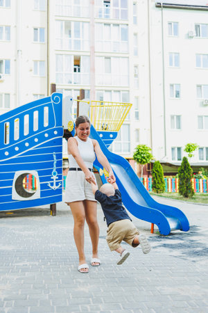 A loving mother is playing with her son on the street. Happy mother and smiling son. Family relations with the child.の写真素材