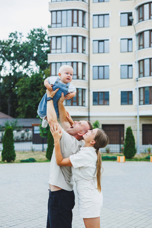 A happy married couple is playing with their son outside on a summer day. The concept of a happy family. Dad, mom and son are playing in the yard.の写真素材