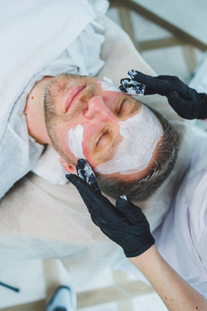 The man is at the dermatologist's appointment. Male cosmetology. Masks for men in a cosmetology clinic.の写真素材