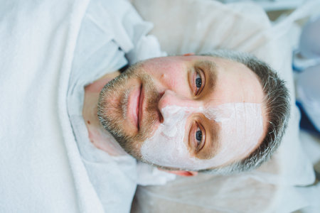 A cosmetologist cleans the skin of a man's face. A man does facial procedures in a cosmetic clinic. Male cosmetology.の写真素材