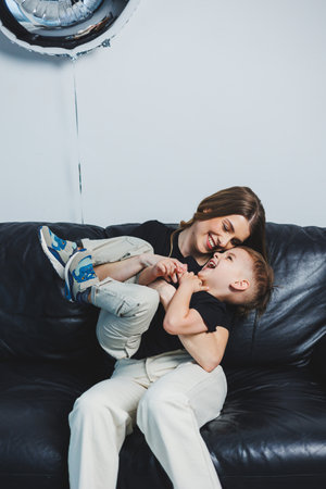Happy mother hugs her little son while sitting on sofa. A mother's love for her son. Family relations with the childの写真素材
