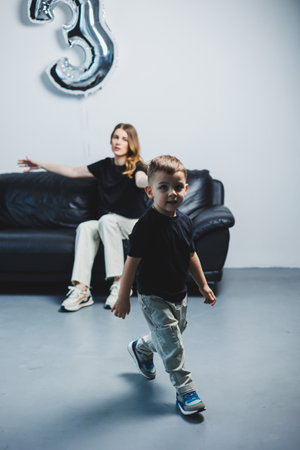 Happy mother hugs her little son while sitting on sofa. A mother's love for her son. Family relations with the childの写真素材