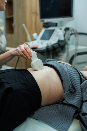 Examination using an ultrasound machine at work. Modern clinical diagnosis and treatment. Ultrasound scanner in the hand of a doctor. Doctor ultrasound examination of the patient's abdomenの写真素材