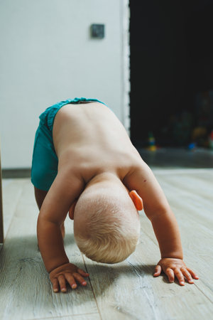 A toddler boy in shorts runs around the apartment at home. The child is playing at home. Active entertainment at home with the child.の写真素材