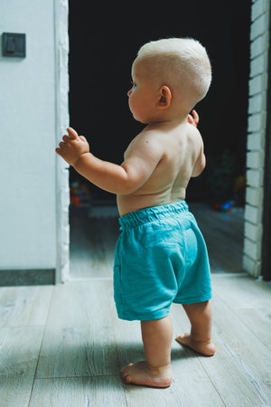 A toddler boy in shorts runs around the apartment at home. The child is playing at home. Active entertainment at home with the child.の写真素材