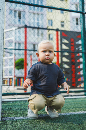 Cute toddler boy lying on green grass. Active time of the child outside. A child runs on the street...