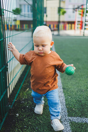 Cute toddler boy running on the soccer field. Active time of the child outside. A child runs on the...