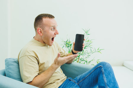 A handsome man sits in a chair and works on the phone. A man is talking on the phone while sitting at home.の写真素材