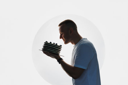 A man in a white T-shirt holds a large cake in his hands. The pastry chef holds a fresh cake in his hands.の写真素材