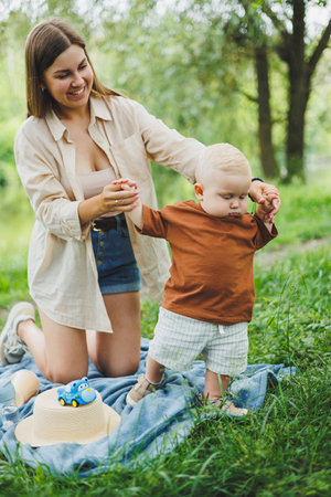 Mother's time with her little son. A young mother is sitting on the grass in the park. A walk of a mother with her son.の写真素材