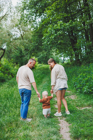 A family couple with a small son are standing in the park on the grass. Mother, father and child...