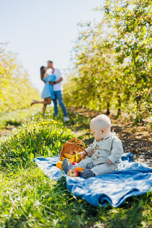 Baby boy sitting outdoors on green grass. A child against the background of his parents.の写真素材