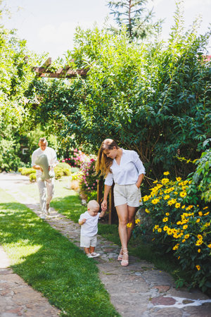 Two parents are playing on a walk with their toddler son. A young married couple, a man, a woman and a little son, are walking in the park. Time for a walk, mom, dad and small child.の写真素材
